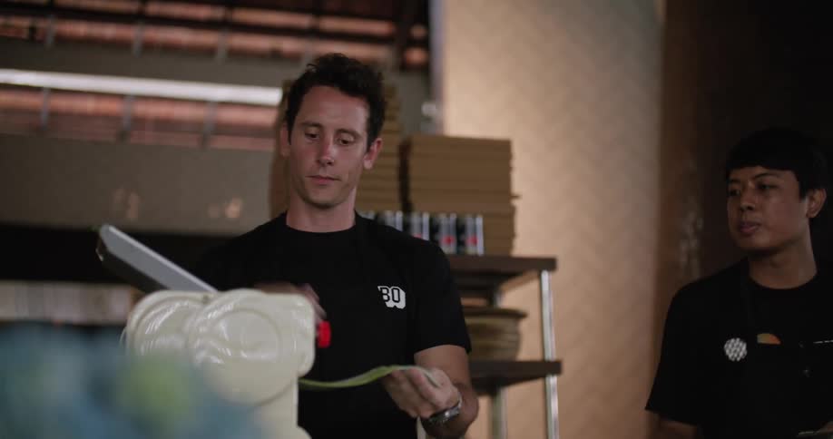 Two people using an appliance to make pasta on a restaurant