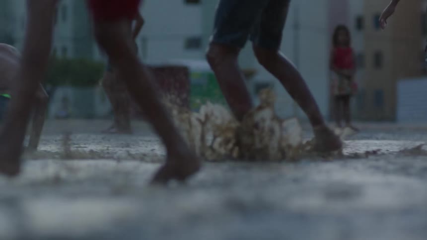 A group of boys are splashing in the water and mud as they play in the rain
