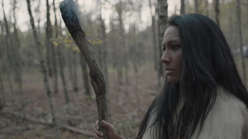 Tribal woman walking through the forest with a smoking branch