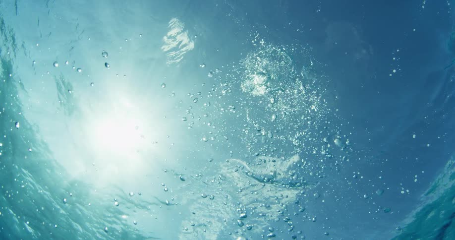 A large air bubble rises underwater towards the surface