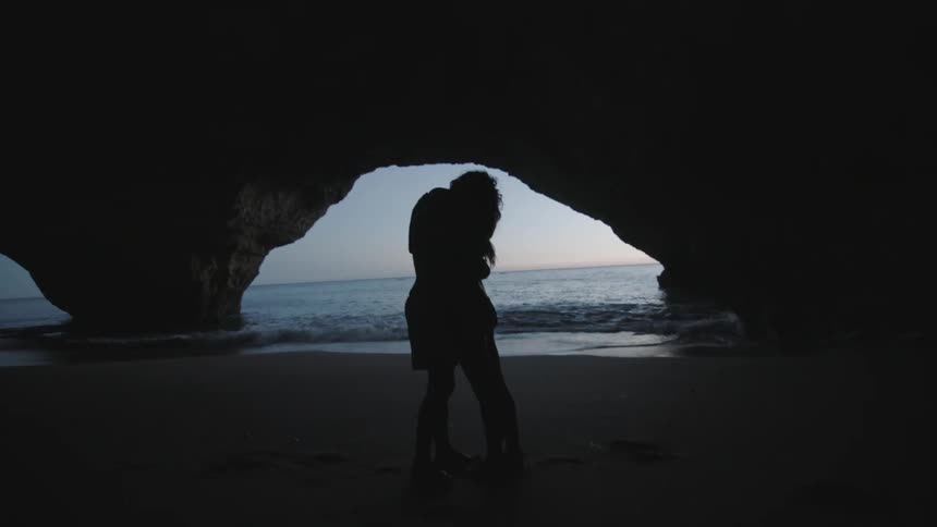 Couple embracing in a cave next to the sea