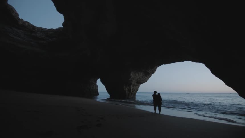 Two people walk along the sand of a beach