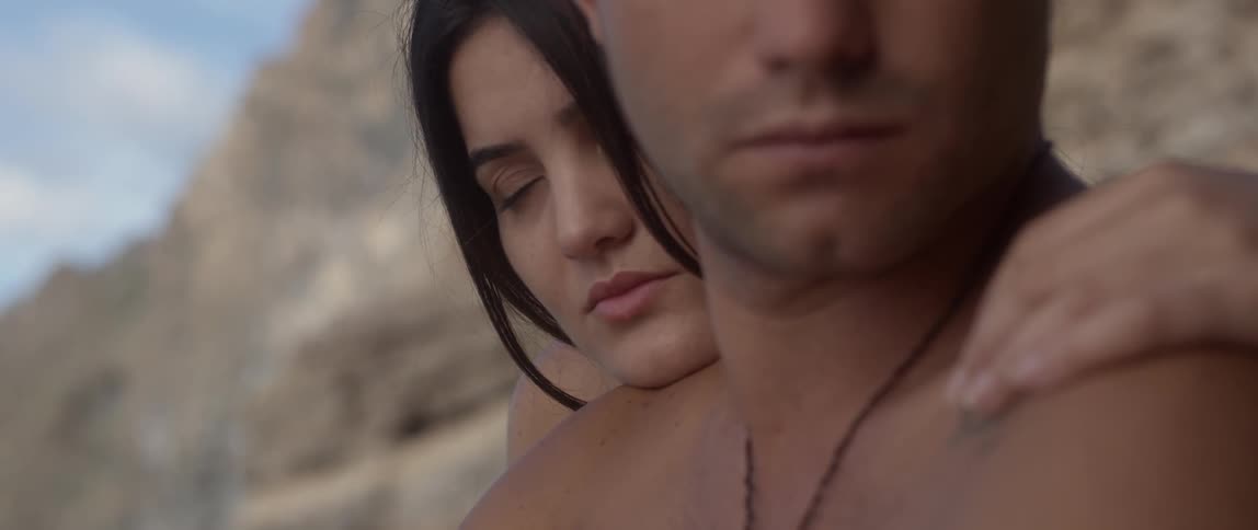 Close-up of a woman resting her head on a man's shoulder while caressing him