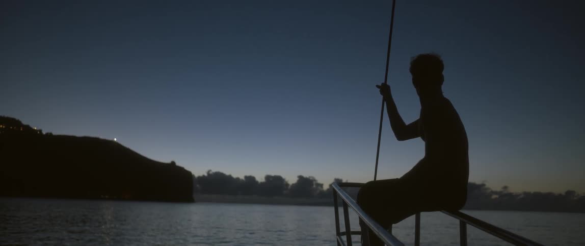 Man sitting on the very front railing of a ship