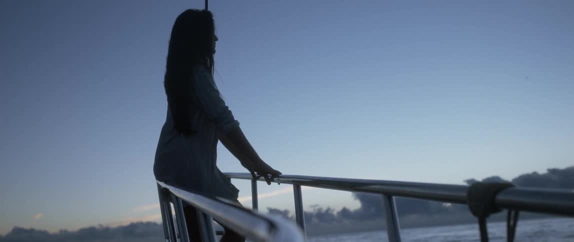 Woman sitting on the railing of a moving ship