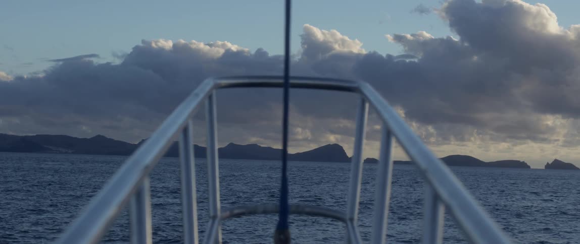 The railing of a boat shows rough waters ahead