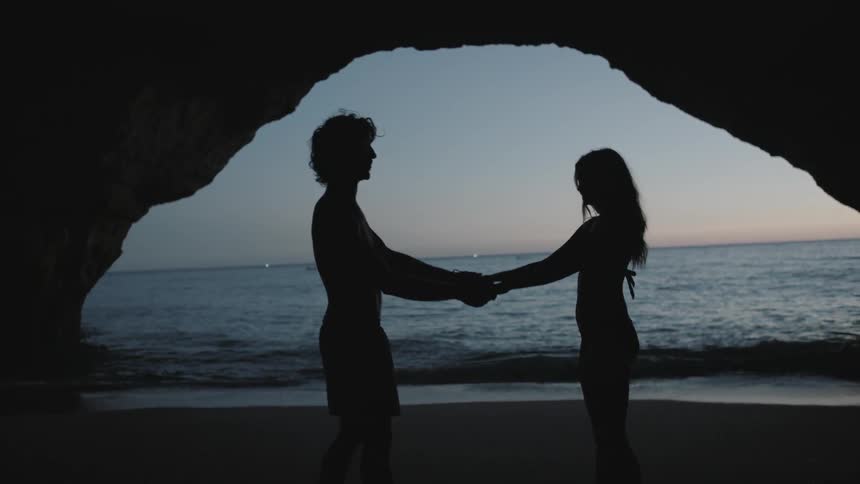 A man and woman hold hands by the water