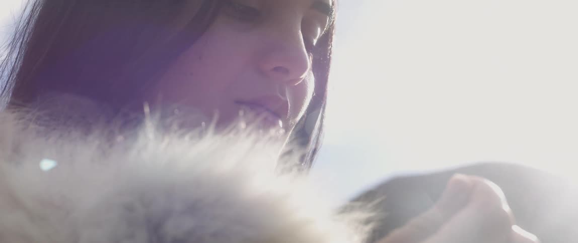 A woman is looking down at something as she wears a boa