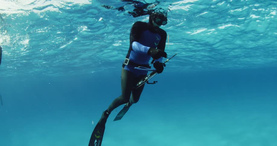 A diver is working with a harpoon gun near the ocean surface