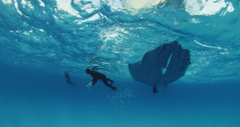 A scuba diver swims near the surface next to a boat
