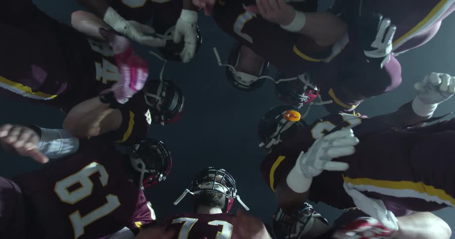 A football team huddles and claps their hands on a sports field