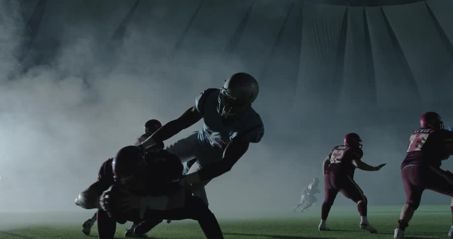 Football teams playing game under dome at night
