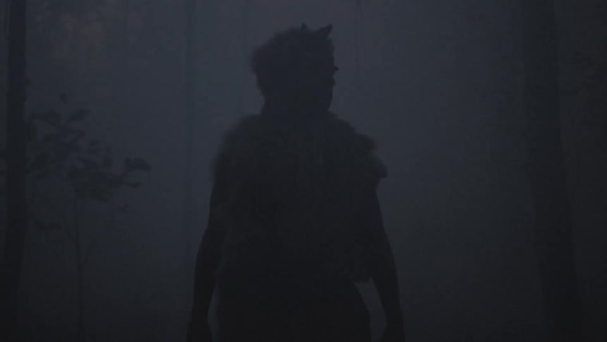 Tribal man standing in a smoky dark wooded area