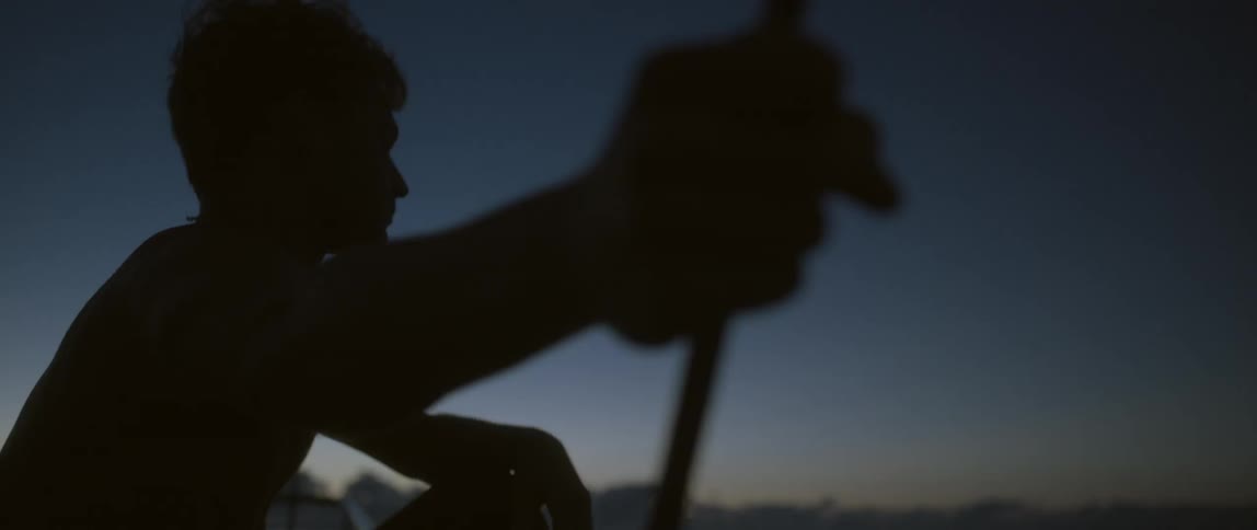 Man standing at a ship's railing holding onto a line