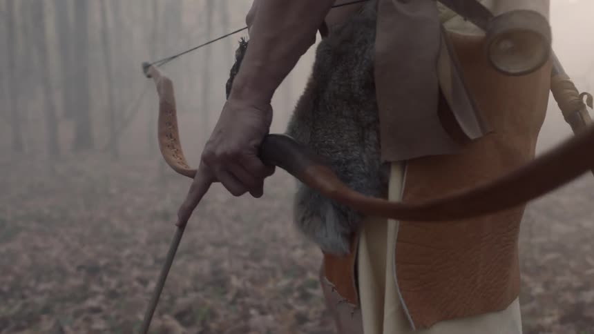 Man carrying bow and arrow walks cautiously