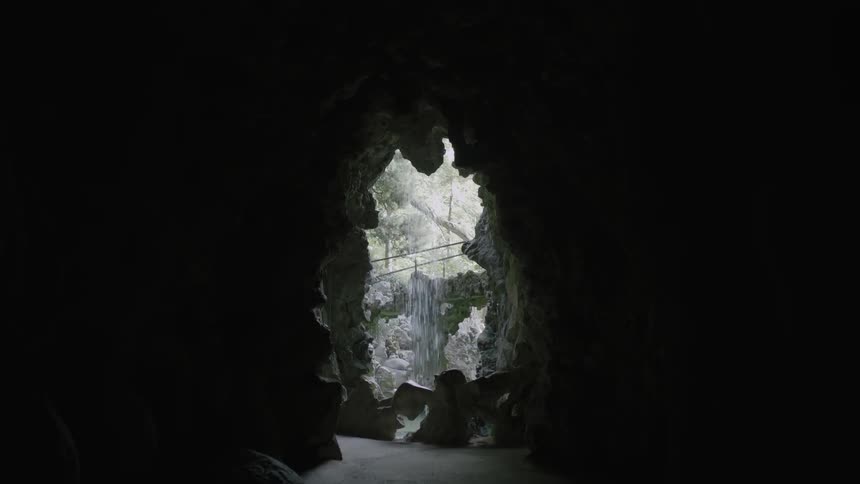 A waterfall spilling down in front of a cave opening