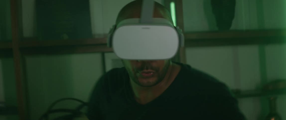 Man wearing a virtual reality headset playing a tennis video games at home