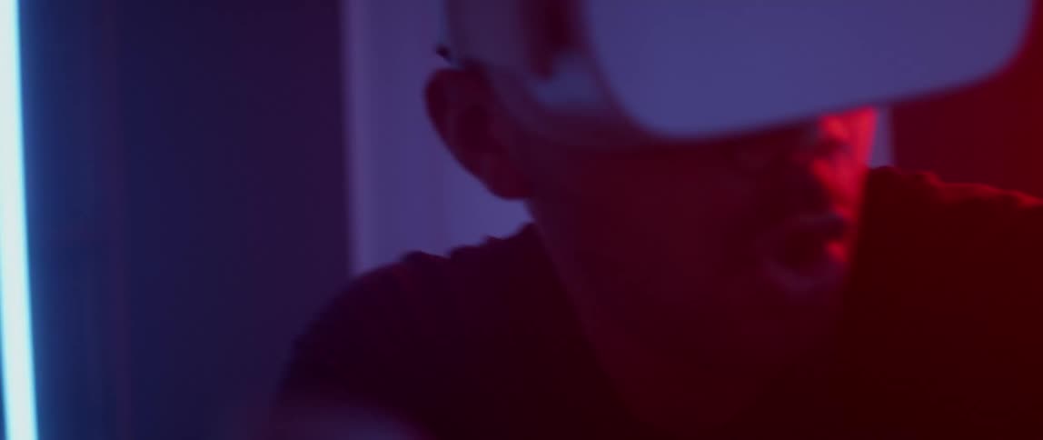 Excited man wearing a virtual reality headset playing a game indoors