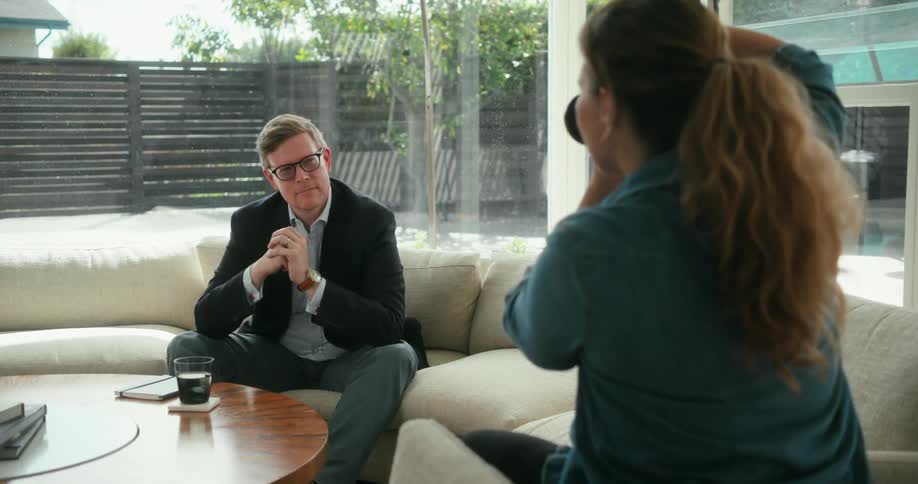Photographer takes pictures of a business man sitting on a couch at home