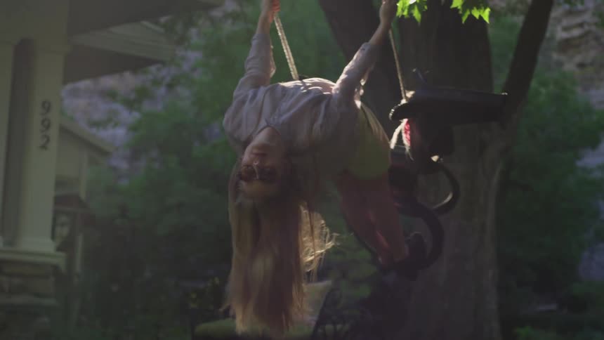 A girl with long hair swinging on a tree swing in a yard