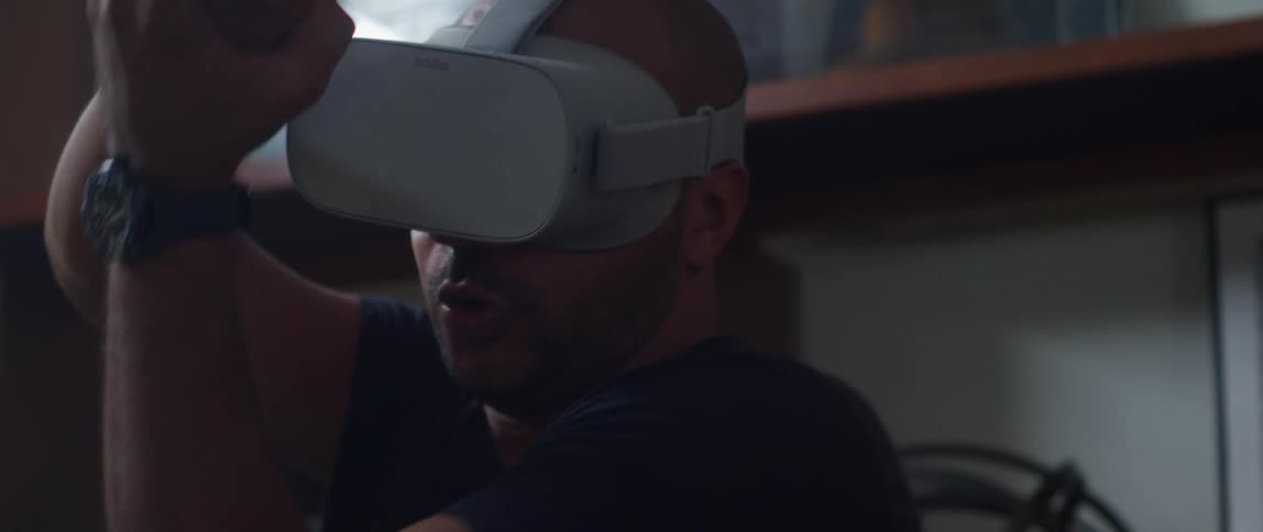 A man looks down at his hands while using a virtual reality headset at home