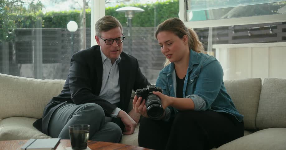 A man and woman looking at photos on the screen of a digital camera