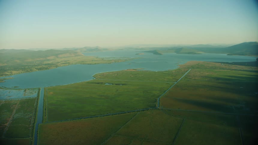 Man made pathways connect to a vast lake and field as seen from 10,000 feet