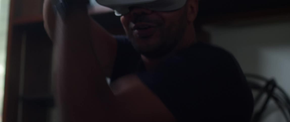 Man wearing virtual goggles smiles while gaming at home