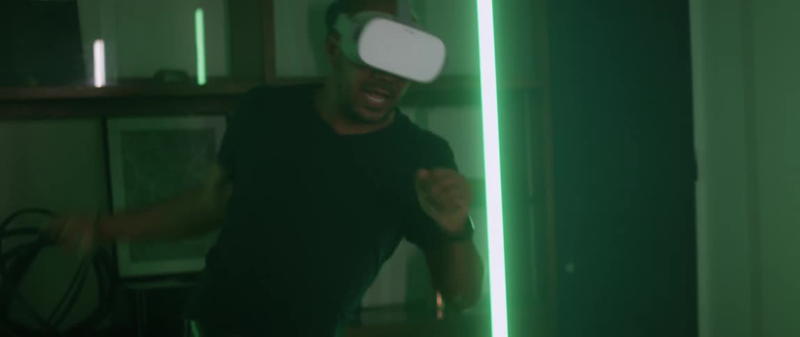 A man smiling and swinging his arm while using a virtual reality headset indoors