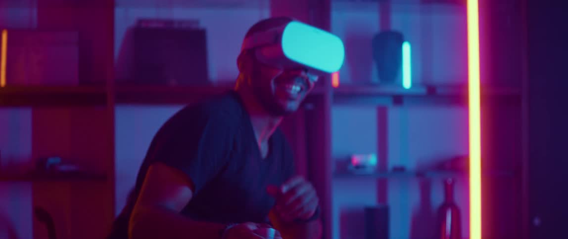 Man wearing a virtual reality headset playing sword fighting video games at home