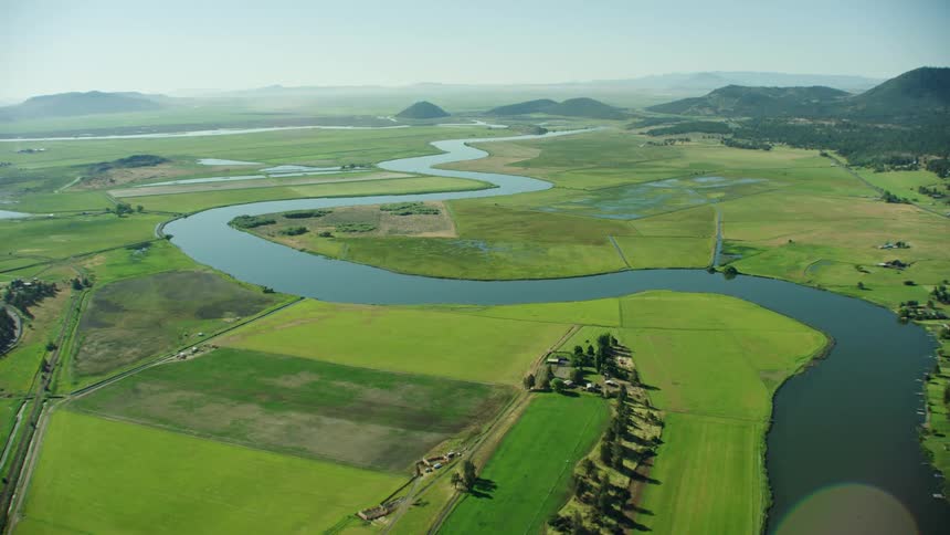 The Klamath River winds through flat agricultural plains in this gorgeous wide shot of a perfect river valley