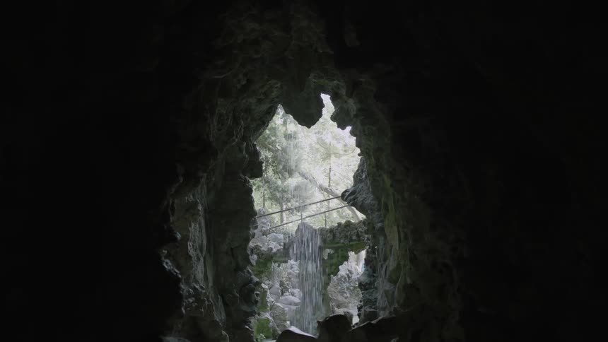 Water flows over the opening of a cave