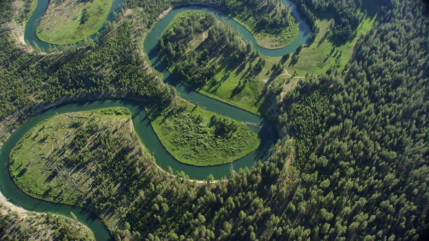 Aerial look down shot of a lazy meandering ox bow river in a high alpine setting