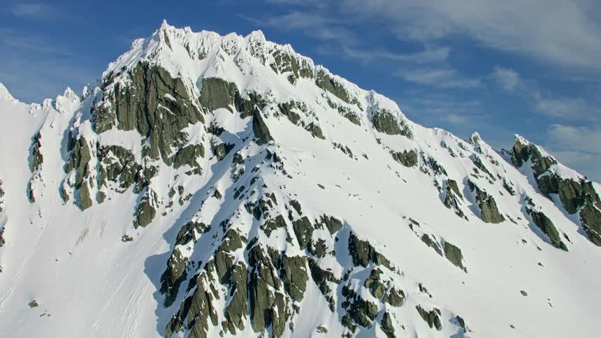 Snow covered mountains with peaks high in a blue cloudy sky