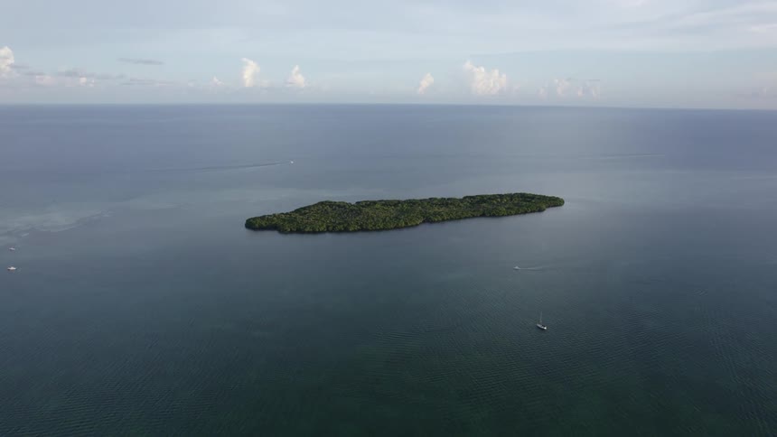 A boat sails away from a small island in the ocean