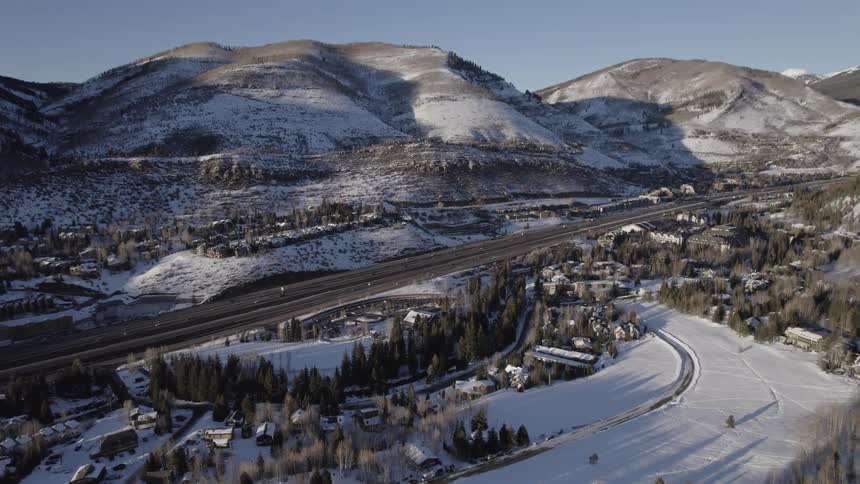 Vehicles drive through a snow covered mountain town