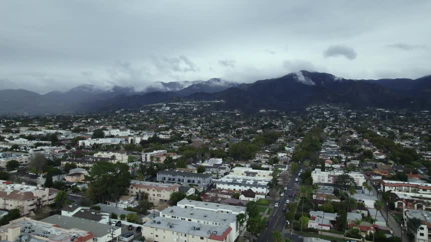 An aerial view shows a sprawling city located in a valley surrounded by mountains