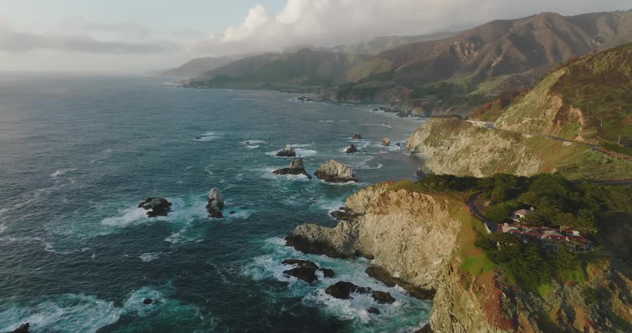 Aerial view of ocean waves breaking against cliffs at bay