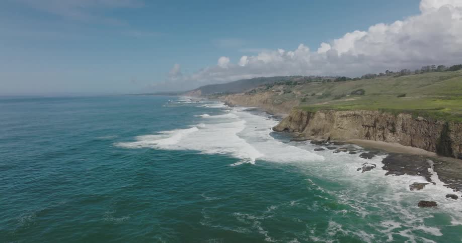 An aerial view of ocean waves flowing towards a shoreline