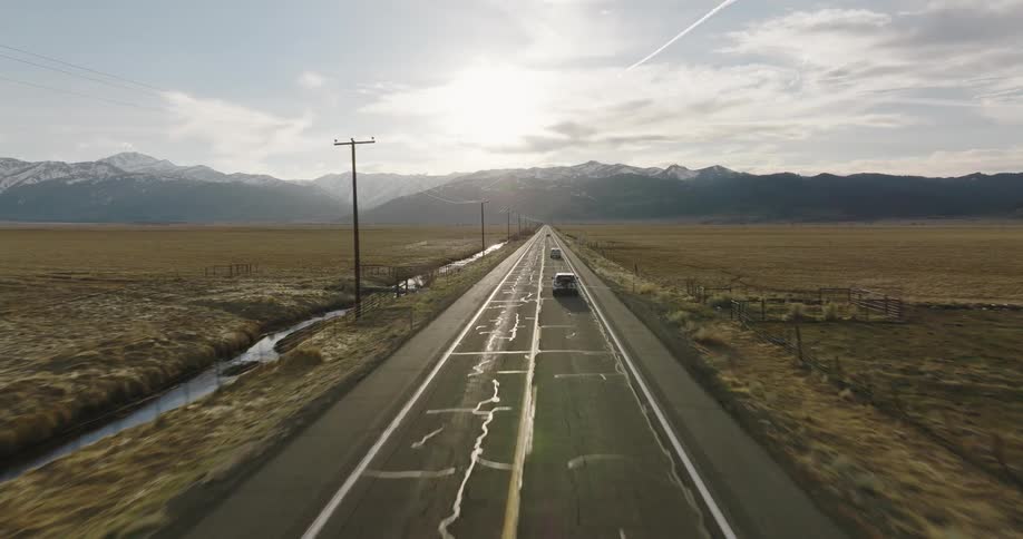 Vehicles are driving on a highway in a rural area