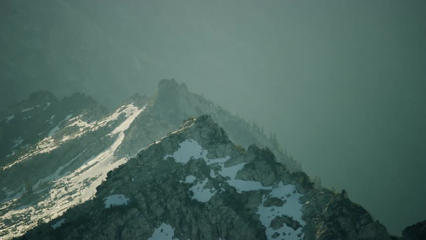 The sun shines upon a mountain peak with thin glaciers holding on in the hot summer sun