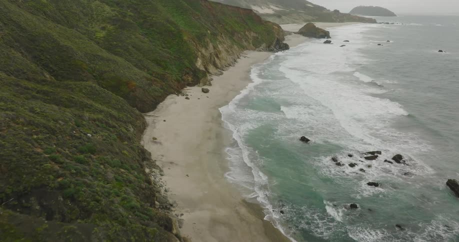 Waves crash onto the beach below tall cliffs