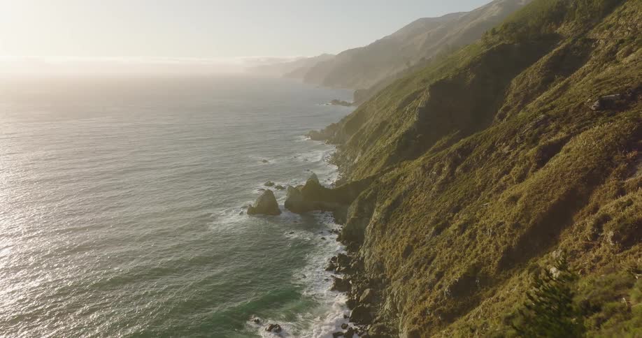 A rocky slope leading down to the ocean on the coast of a landmass during the day