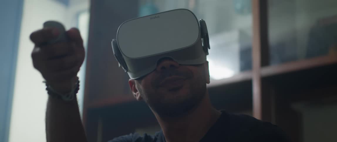 Man sitting on a couch at home wearing a virtual reality headset playing video games at home