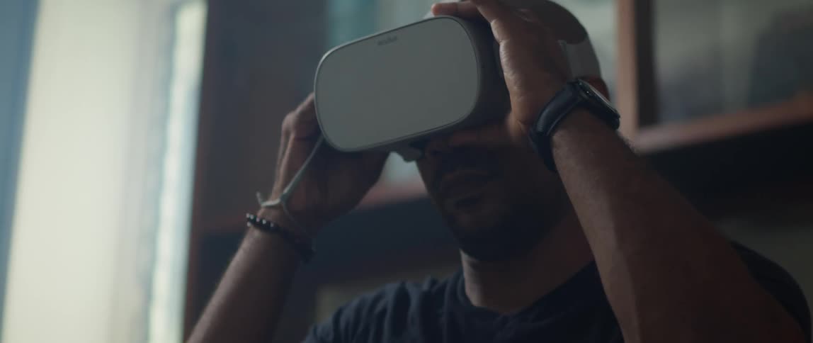 A man puts on a virtual reality headset at home