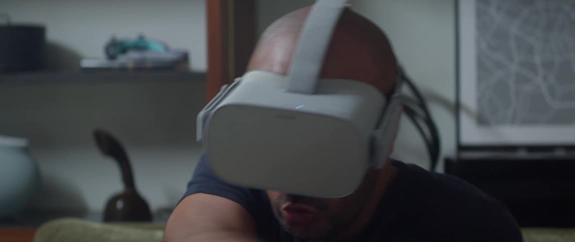 A man makes sword swinging motions while playing a game on a virtual reality headset