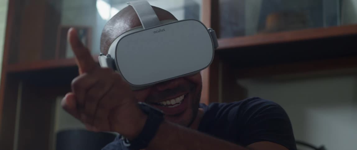 A man smiling and laughing while playing a game on a virtual reality headset