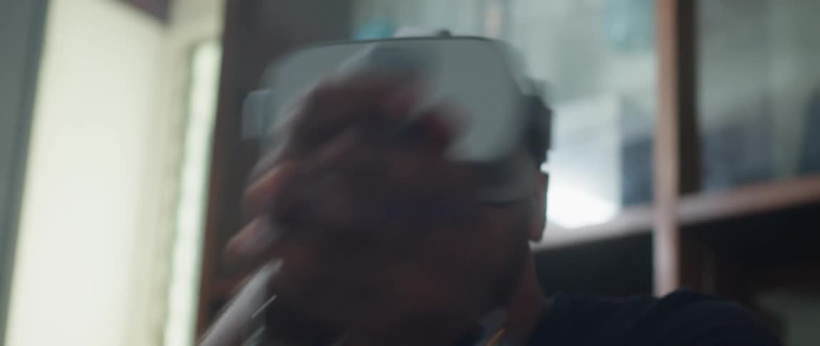 Man sitting on a couch wearing a virtual reality headset playing video games at home