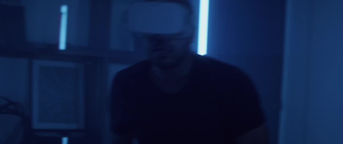 A man wearing a virtual reality headset looks around quickly and aims his controller like a gun