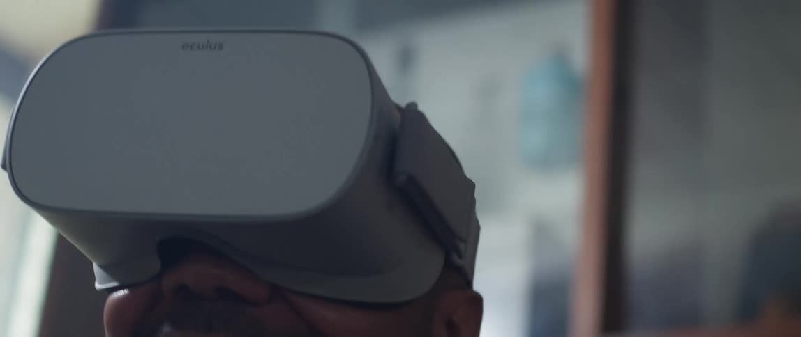 Man sitting on a couch at home wearing a virtual reality headset playing video games at home